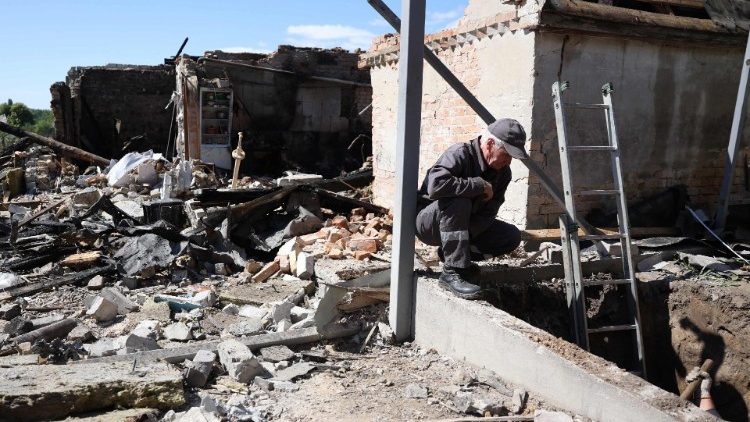 Trabalhadores de serviços públicos trabalham perto de uma casa particular destruída por um ataque de mísseis na aldeia de Krasylivka, região de Kiev, em 8 de maio de 2024, em meio à invasão russa na Ucrânia. (Foto de Anatolii STEPANOV/AFP)