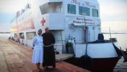 La hermana Marcia Lopes Assis frente al “Barco Hospital Papa Francisco”, junto a Fray Afonso Lambert, coordinador de los trabajos.