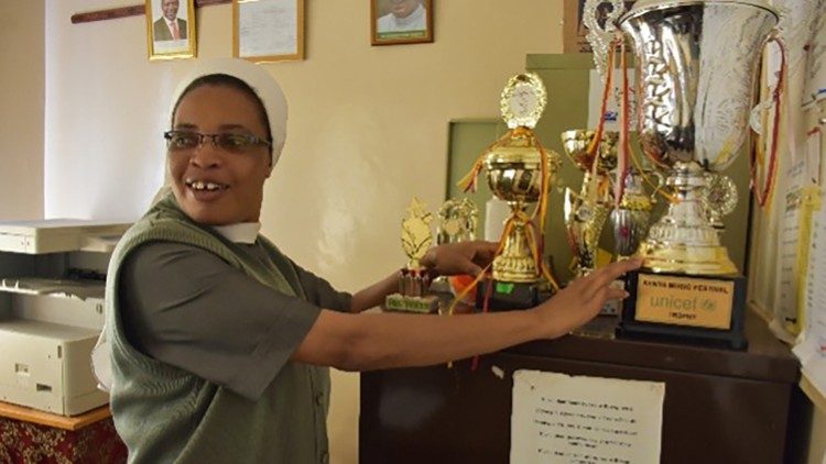 A Ir. Rose Marie Gatimu, diretora da escola, mostra troféus conquistados pelos alunos em atividades curriculares